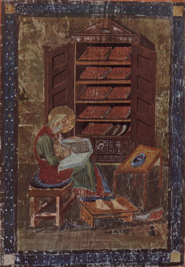 Medieval manuscript image of a man with a halo writing in a book, with a cabinet of books behind him.
