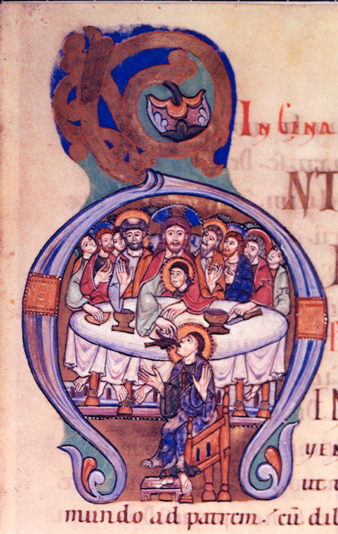 Medieval manuscript image of the letter A showing the Last Supper. Christ passes a sop to Judas who sits on the other side of the table from Christ and the other Apostles. At this moment, Satan, shown here in the form of a black bird, enters Judas. 