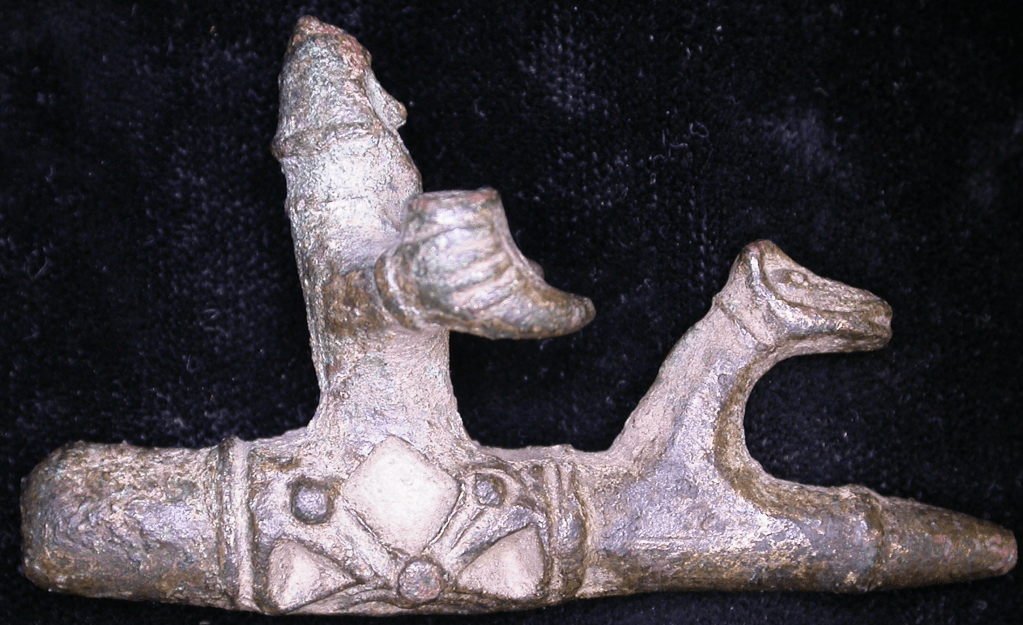 Metal object with a rounded point shaped like a man holding a drinking horn while sitting on a horse.