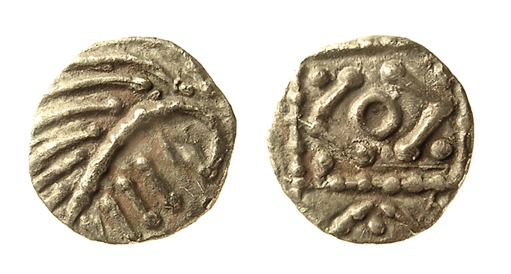 The front and back of a silver coin: on one side is a ‘porcupine’ bust and on the other is a square standard with beaded border, annulet at centre with V to either side, a pellet in each corner of the standard, and to one side of the standard a V with pellet above.