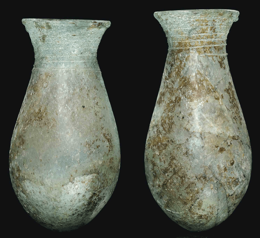 Two greenish-blue opaque glass bottles with elongated bulbous bodies and flaring mouths, decorated below the rim with a band of spiral trailing.