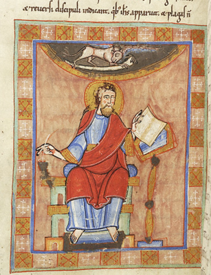Medieval manuscript image of a haloed man sitting on a cushioned bench with feet on a footstool, with right hand dipping a pen into an ink-horn and with the left holding a book open on a lectern; a winged ox floats above holding a scroll.
