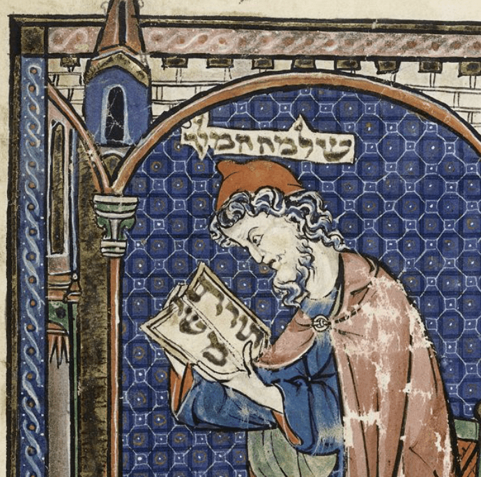 Medieval manuscript image of a grey-haired, bearded man studying a book written in Hebrew.